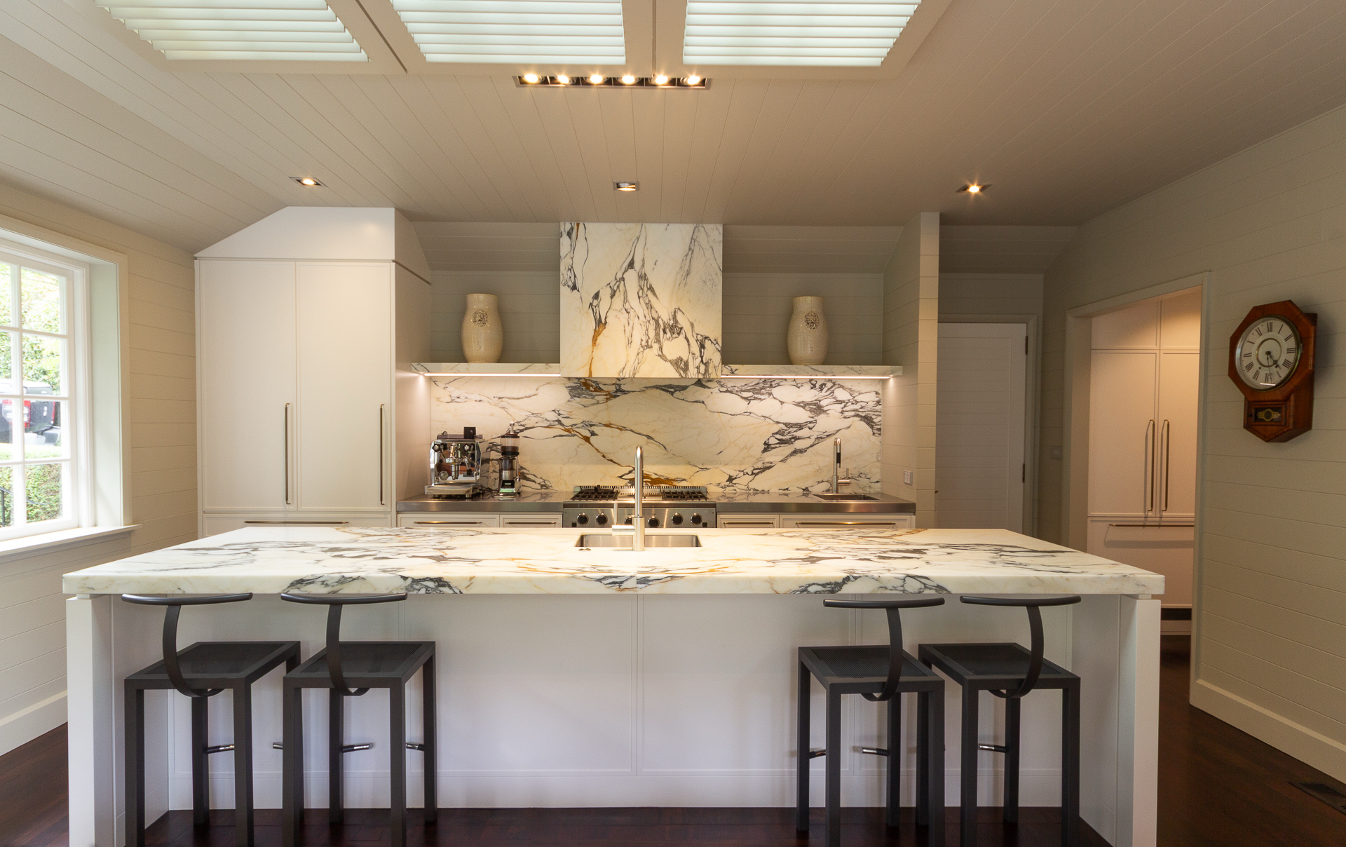 Luxury kitchen interior with calacatta marble island, bar stools, and skylight — Design in Residence Wellington